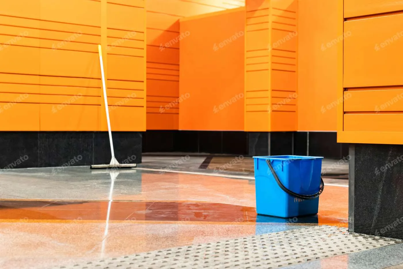 img-24-hour-services Wet floor with a squeegee and blue bucket in a brightly colored facility after a government cleaning service.
